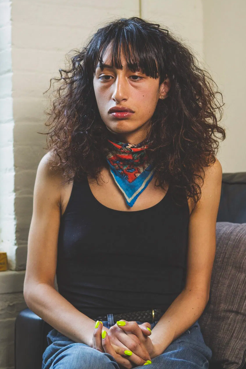 Transgender woman sitting on a therapist's couch looking upset